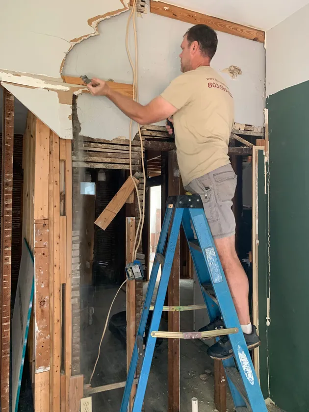 Interior Demolition Worker During Renovation Interior demolition worker on a step ladder removing materials during a renovation project