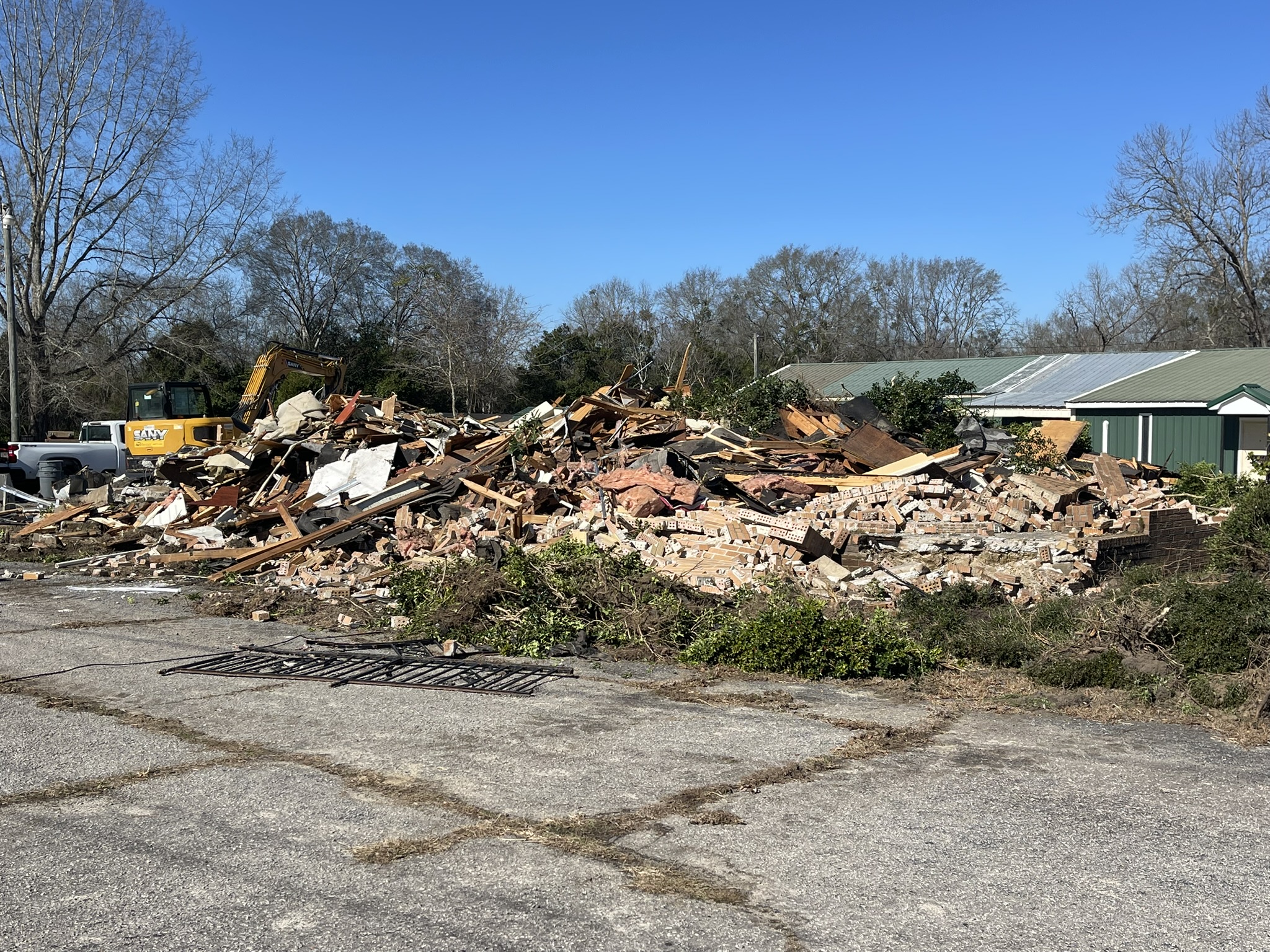 Commercial demolition in progress in Denmark SC with excavator and debris from brick building