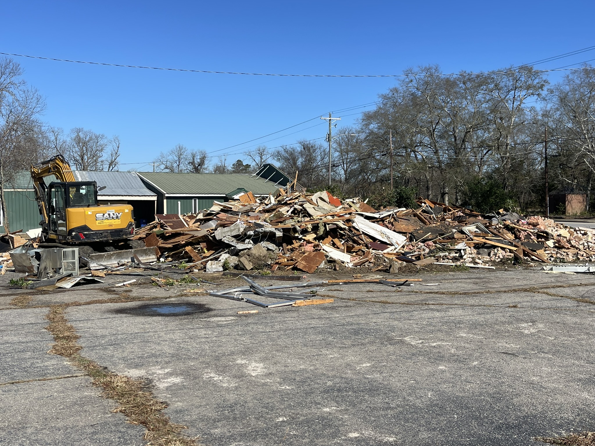 Commercial building demolition progress in Denmark SC with debris pile and excavator