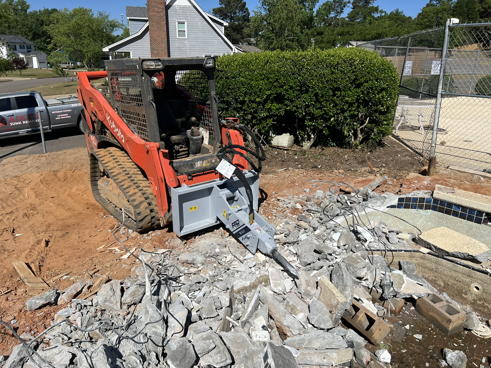 Skid steer with hydraulic breaker used for thick concrete spa removal in Aiken SC